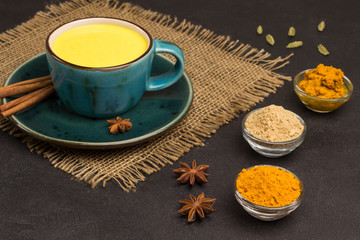 Herbal therapy concept.  Golden latte with ingredients for cooking: ginger and turmeric powder, turmeric paste, cardamom, cinnamon sticks, star anise
