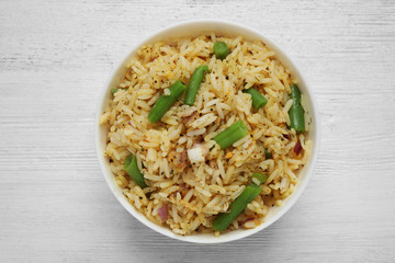Tasty rice pilaf with vegetables on white wooden table, top view