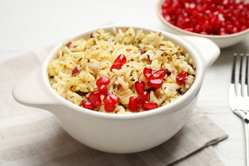 Tasty rice pilaf with pomegranate grains on table, closeup