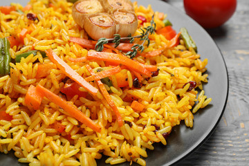 Tasty rice pilaf with vegetables on grey wooden table, closeup