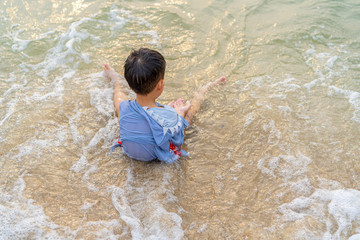 A boy is playing sand and swimming with his brother on the beach.