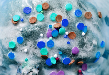 Sugar colored confetti lies on a white icing rustic cake, texture of sugar icing on a cupcake surface close-up