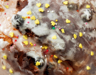 Sugar colored confetti lies on a white icing rustic cake, texture of sugar icing on a cupcake surface close-up, pink, blue and white candy