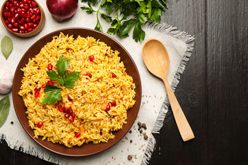 Tasty rice pilaf with pomegranate grains served on black wooden table, flat lay