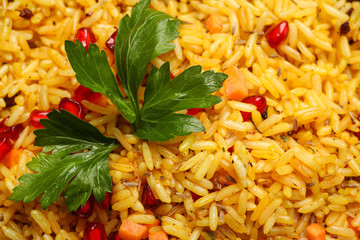 Tasty rice pilaf with pomegranate grains and parsley as background, closeup
