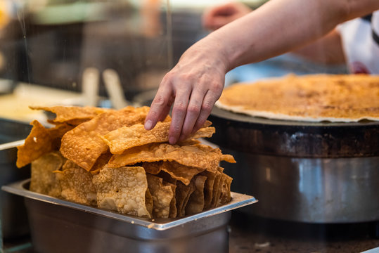 Closeup of person cooking crepe crespelle traditional dessert in Florence, Italy in famous market and hand picking up deep fried cracker