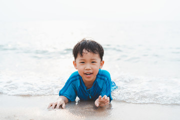 A boy is playing sand and swimming with his brother on the beach.