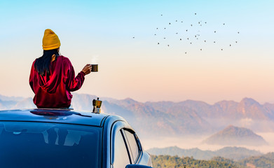 Woman traveller enjoy coffee time on her owns roof of the car with scenery view of the mountain and...