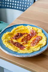 Omelette with Prosciutto Ham Jamon Crudo in Breakfast Plate on Wooden Kitchen Table.