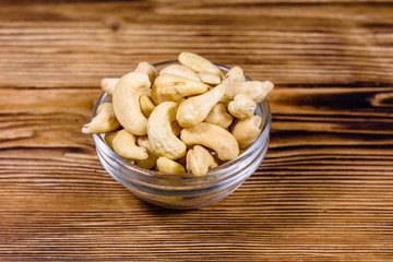 Glass bowl with raw cashew nuts on a wooden table