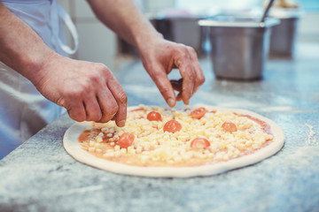 Chef putting tomatoes on an Italian pizza