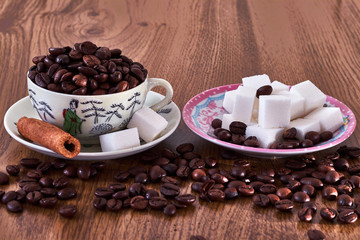 Vintage coffee cup with coffee beans, next to saucer with sugar cubes