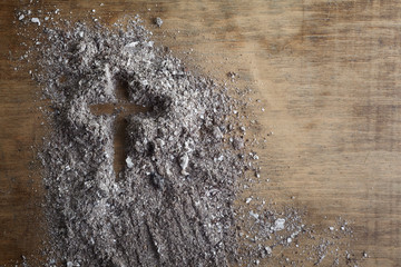 Christian cross symbol made of ash on a wooden background