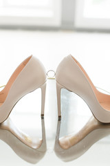 White wedding high-heeled shoes with an engagement ring. Diamond ring between shoes. Wedding.