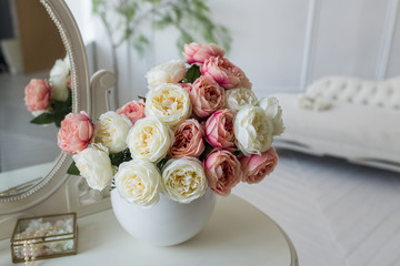 White and pink flowers in a white vase. Roses on the table. Home