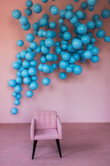 A pink velvet armchair stands against a pink wall with blue balls. Stylish interior. Chair