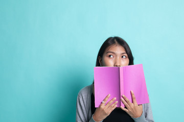 Naklejka premium Young Asian woman with a book cover her face.