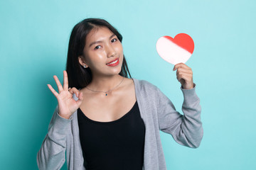 Asian woman show OK with red heart.
