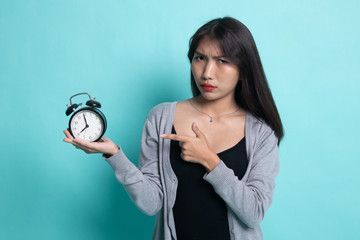 Angry young Asian woman point to a clock.