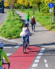 Radfahrer fahren vom Radweg auf einen kombinierten Rad- und Gehweg mit Fußgängern