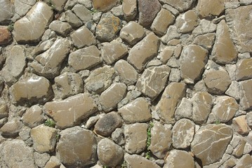 Fragment of an old city street pavement. Street paved by cobblestone. Cobbled texture