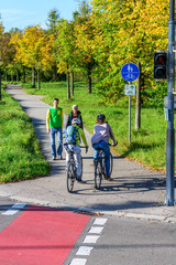 Radfahrer fahren vom Radweg auf einen kombinierten Rad- und Gehweg mit Fußgängern