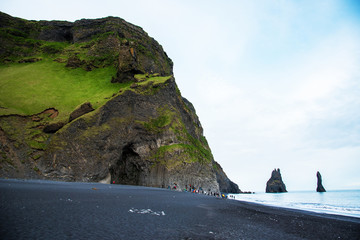 Beautiful dramatic landscape with cave in basalt rock on the black sand beach on Reynisdrangar Sea...