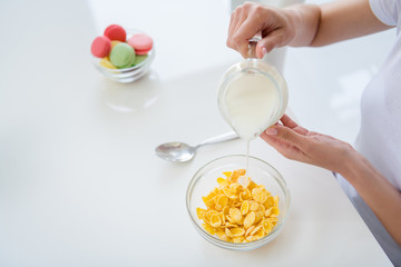 Cropped photo of housewife hands holding pouring milk jug cooking breakfast cornflakes healthy eating concept keeping to diet ignore sweets white light kitchen indoors