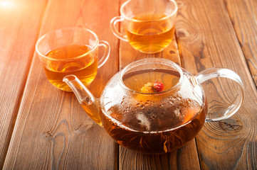 Knitted blooming tea in a transparent teapot close-up. Tea ceremony on a dark wooden background and copy space.