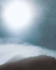 Obraz premium Mist over mountain trail in Auvergne with sun passing through clouds