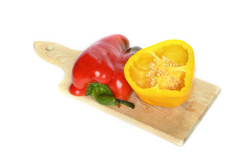 yellow and red peppers on wooden cutting board, isolated on white background