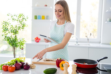 Photo of charming housewife enjoy weekend morning cooking holding e-book checking recipe directing finger onion online cook book white kitchen indoors