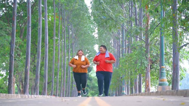 Attractive overweight couple running at the park while talking to each others. Shot in 4k resolution