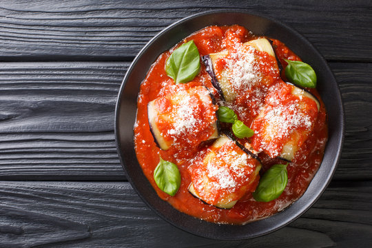 eggplant rolls stuffed with ricotta and baked in tomato sauce and served with parmesan and basil close-up in a plate. Horizontal top view - Powered by Adobe