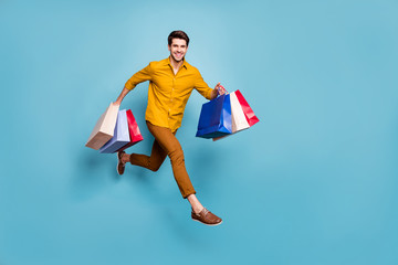 Full length profile photo of funny guy jumping high running fast carry many bags rushing next shop...