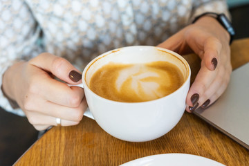 Woman holding a cup of cappuccino