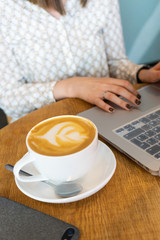The girl works on the computer and drinks coffee