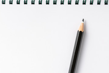 notebook with black pencil on white table top view