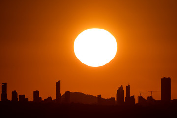 Sunset with big sun over Benidorm city skyline in Alicante