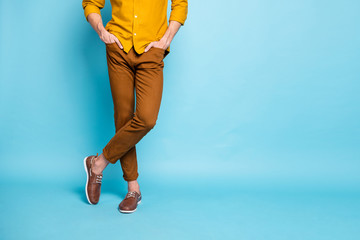 Cropped photo of confident man legs in footwear crossed with hands in pockets standing confidently...