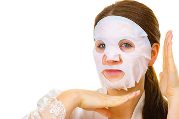 Woman applying sheet mask on face