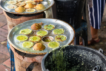 Making fresh coconut pancakes, They are made from coconut cream, rice flour and sugar, Pouring cream in the pan on stove, Sweet street snacks, Luang prabang, Laos.
