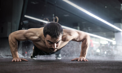 Fototapeta na wymiar Sport. Handsome man doing push ups exercise with one hand in fitness gym. 