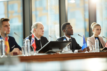 Group of business people sitting at the table and listening during business conference