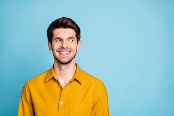 Photo of cheerful nice creative young guy freelancer in yellow shirt looking into empty space smiling toothily isolated over blue pastel color background