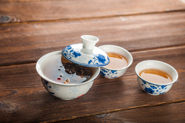 Knitted blooming tea in a porcelain teapot close-up. Tea ceremony on a dark wooden background and copy space.