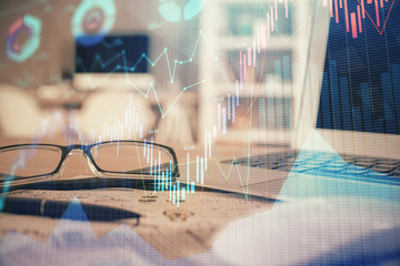 Financial chart hologram with glasses on the table background. Concept of business. Double exposure.