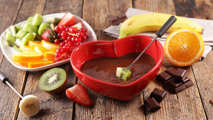 delicious chocolate fondue with fresh fruit in red heart bowl