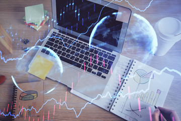 Double exposure of man's hands writing notes of stock market with forex chart.