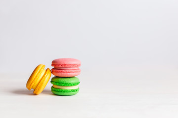Tasty French macarons on a white wooden table. Multicolored macarons. White background.